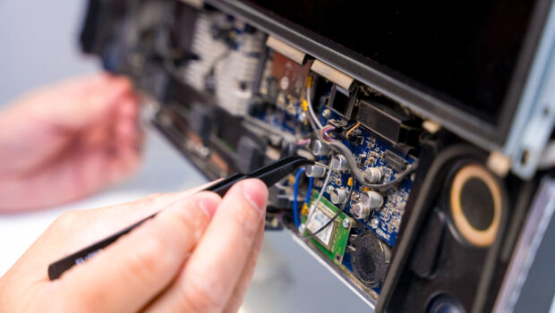 Close-up of the hands of a repairman fixing a computer in a workshop